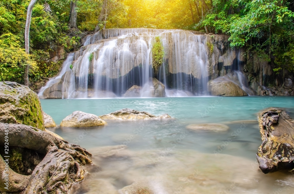 Obraz premium Deep forest waterfall at Erawan waterfall, beautiful waterfall with sunlight rays in deep forest, Erawan National Park in Kanchanaburi, Thailand