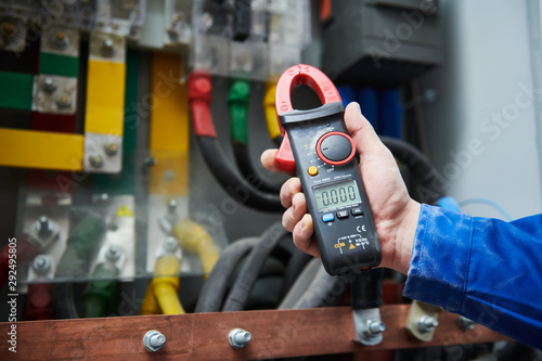 Electrician work concept. Hand with multimeter tester in switchbox photo