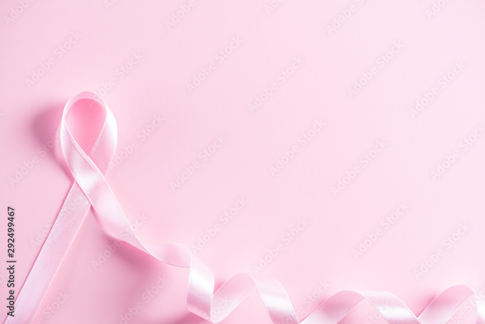 Pink ribbon on pink pastel paper background for supporting breast cancer awareness month campaign.