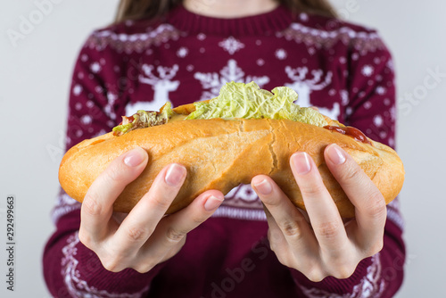 Unhealthy eating food concept. Cropped closeup photo of happy cheerful excited teenager holding large sandwich in hands trying to make two halves isolated grey background