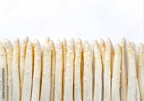 Raw white Asparagus beaded in a row as close-up with copy space at top – isolated on white background