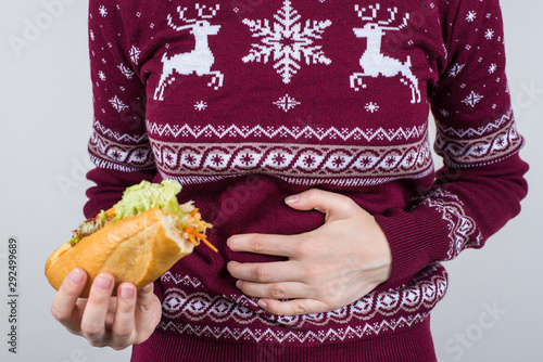 Appendix appendicitis side pain concept. Cropped close up photo of unhappy sad crying suffering from acute pain girl holding half of sandwich in hand isolated grey background