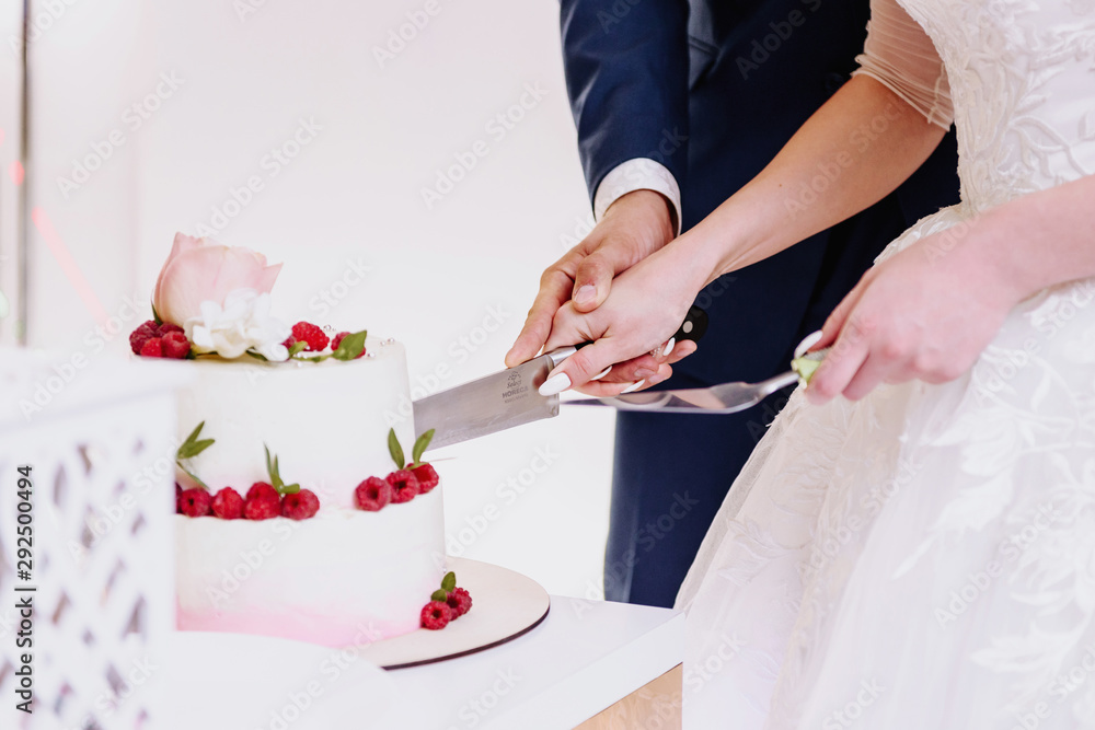 Hands of the bride and groom cut a wedding cake close-up Hands of the bride and groom cut a wedding cake close-up