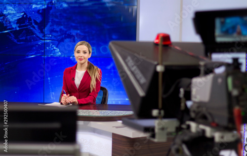 News anchor in the TV Studio . Beautiful girl reading the news, on a blue screen background