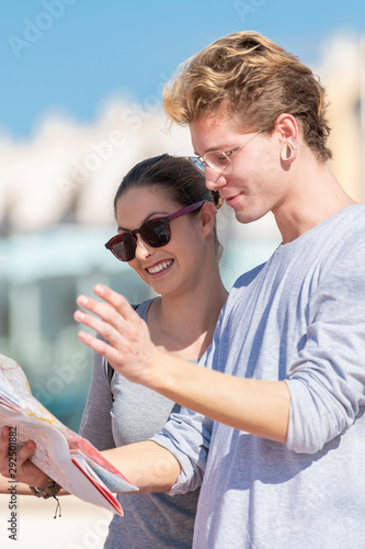 Amazing young boys looking at map in a smiling way she wearing grey shirt and black glasses and eluding grey shirt with expression of doubt with blurred background. © JeanPaul