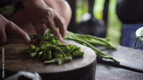 Yardlong bean get slicing by a knife in old lady hands. static shot. photo
