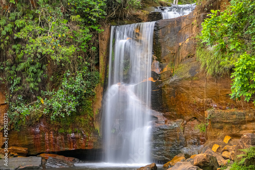 Idyllic waterfall with water motion blur n lush vegetation  red rock formations  Chapada dos Guimar  es  Mato Grosso  Brazil  South America
