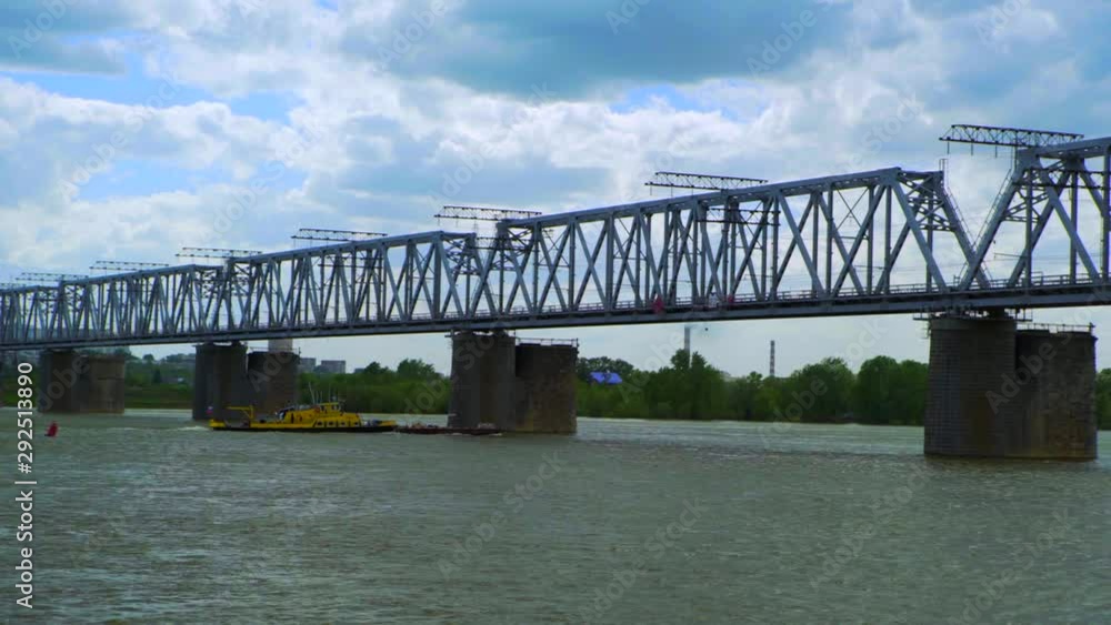 Pan: Boat passing under railway bridge over ob river against cloudy sky - Novosibirsk, Russia Pan: Boat passing under railway bridge over ob river against cloudy sky - Novosibirsk, Russia