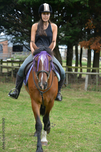 Pretty oung woman riding her horse on sunny summers day.