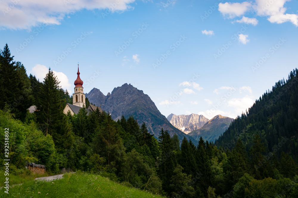 Kaunertal (Kaltenbrunn, Austria) landscape with the Unserer Lieben Frau Mariä Himmelfahrt church (Our lady of the Assumption). Woods and Alps on the background