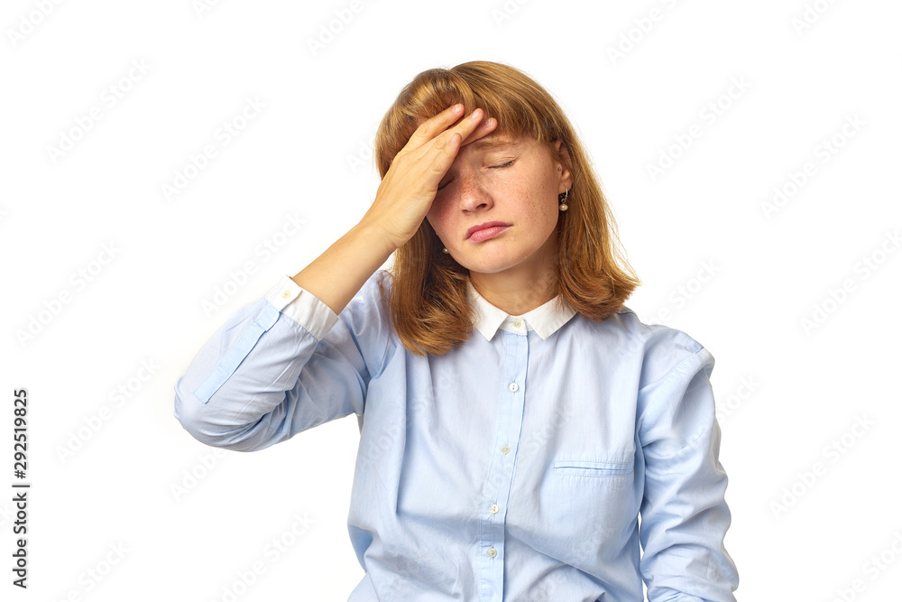 Young girl with ginger hair and freckles touching her head as having a headache our feeling tired, overwhelmed with noises. White background, copy space, isolated model. Young girl with ginger hair and freckles touching her head as having a headache our feeling tired, overwhelmed with noises. White background, copy space, isolated model.