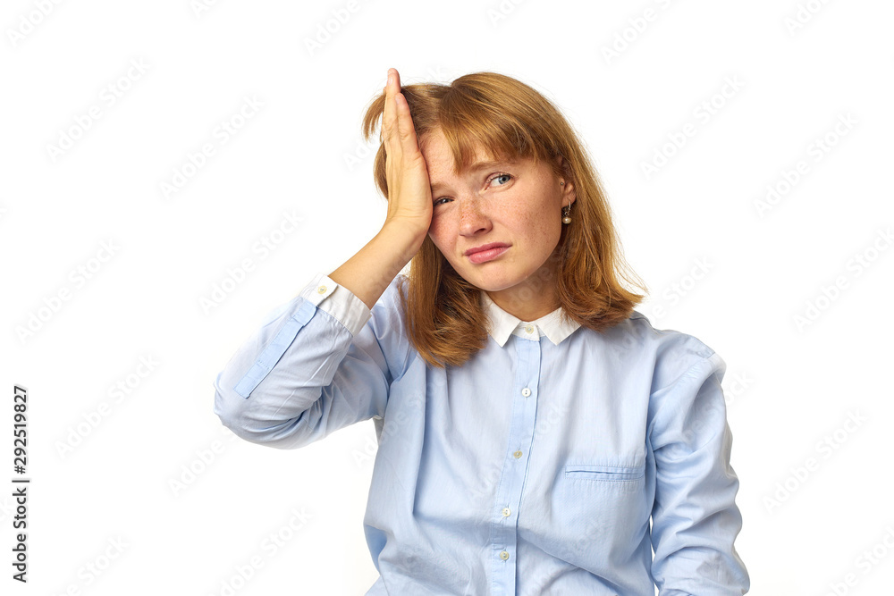 Young girl with ginger hair and freckles touching her head as having a headache our feeling tired, overwhelmed with noises. White background, copy space, isolated model. Young girl with ginger hair and freckles touching her head as having a headache our feeling tired, overwhelmed with noises. White background, copy space, isolated model.
