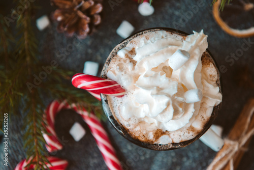 mug of hot chocolate with whipped cream  marshmallows and red Lollipop on a black background  hot winter drink 