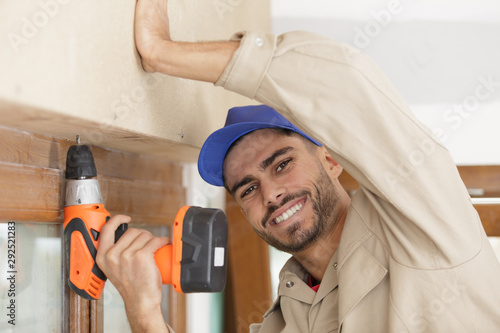 happy man drilling a hole in a window frame