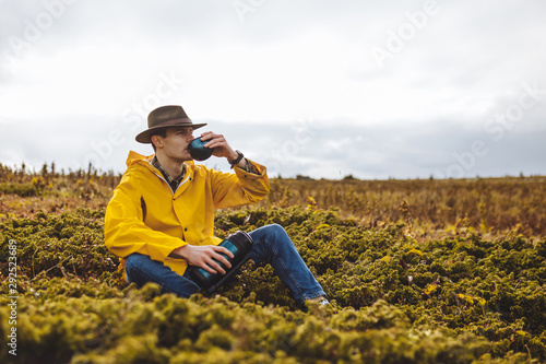 young man drinking tea while sitting on the grass  close up photo. copy space  copy space