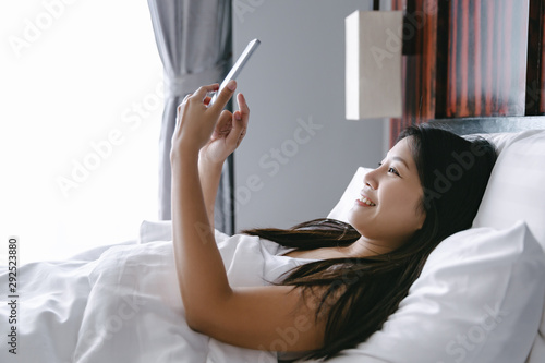 Woman with mobile phone on bed