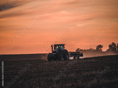 Tractor on filed by sunset.