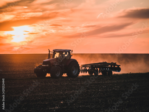Fototapeta Naklejka Na Ścianę i Meble -  Tractor on filed by sunset.