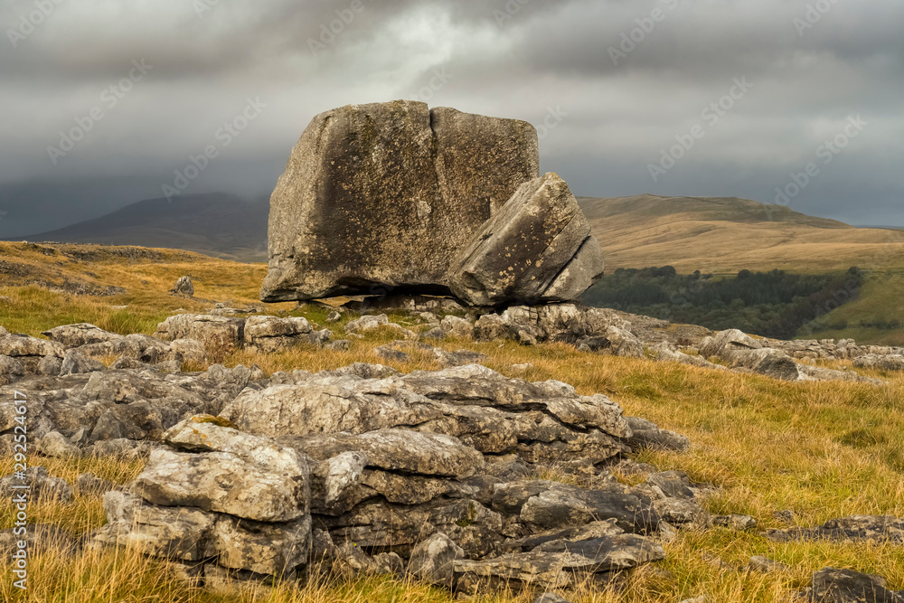 The Cheese Press Stone above Ingleton and with brooding Ingleborough in the background. These stones are 'fragments' of the magnificent limestone scenery of the Yorkshire Dales.