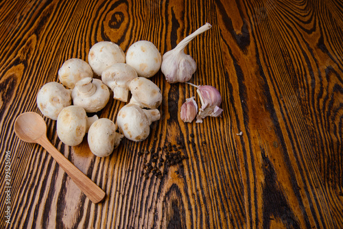 composition poured olive oil, mushrooms, garlic on wooden background photo