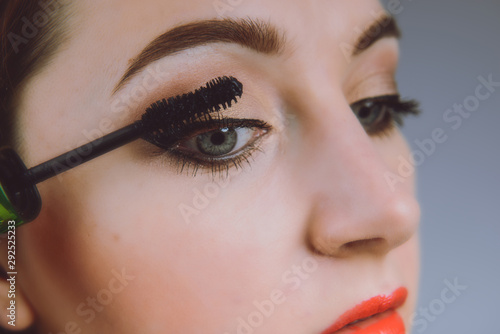 Beauty model teenage girl looking in the mirror and applying mascara make up. Beautiful young woman apply makeup