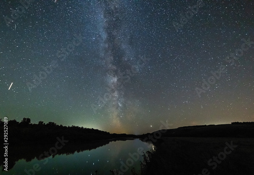 Billede på lærred The stars and the milky way are reflected in the river.