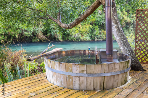 Leisure time at an idyllic wooden hot tub inside a fantasy green scenery with Caburgua river stream flowing inside an amazing rainforest full of trees during morning time a moody atmosphere background © abriendomundo