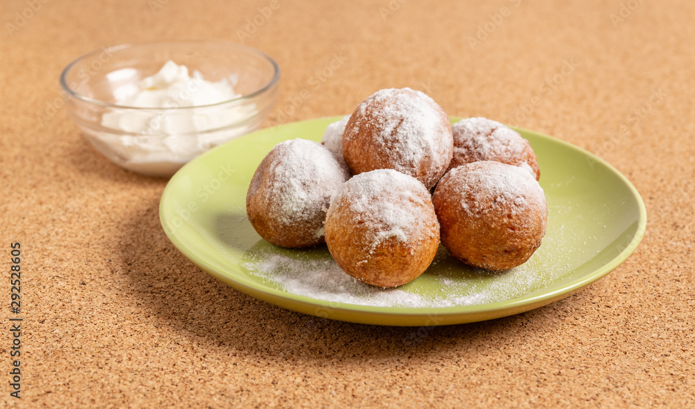 Round doughnuts, sprinkled with powdered sugar, lie on a plate Round doughnuts, sprinkled with powdered sugar, lie on a plate