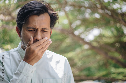 Halitosis , young asian man is checking his breath with his hands. Mouth health problems photo