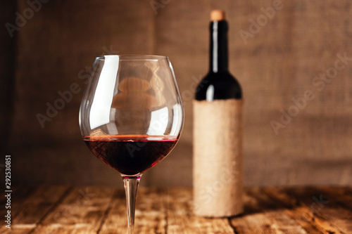 Red wine in a wine glass on the background of a wine bottle.