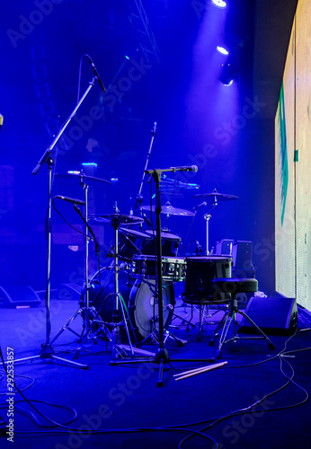 Set of drums and microphones with sound portal on the stage in blue smoke before the concert