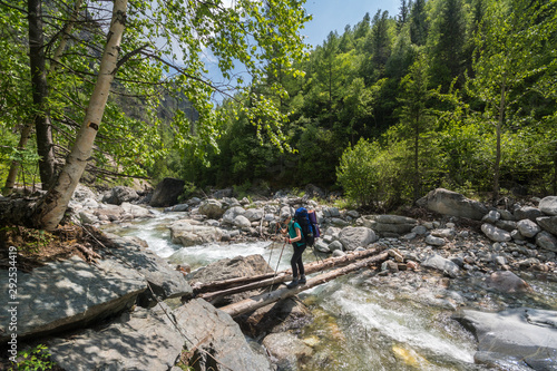 The girl crosses the mountain river on a wooden bridge