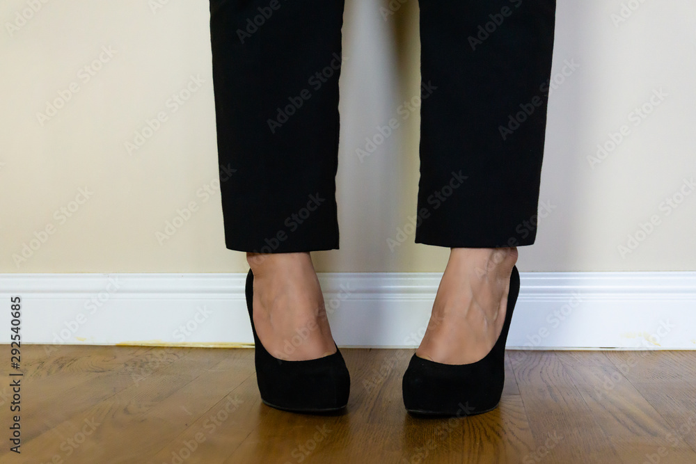 Close-up of woman's legs in high-heeled black shoes on parquet Close-up of woman's legs in high-heeled black shoes on parquet