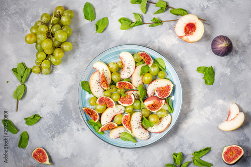 Fresh fruit and berry salad with grapes, fig and peach on concrete background. Healthy food.