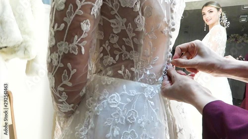 Young bride put on a wedding dress in the salon for fitting.