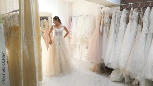 Young beautiful woman measures wedding dress in a bridal salon.