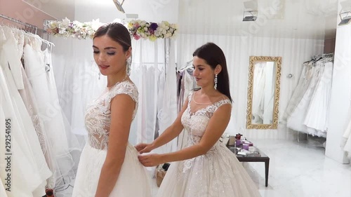 Two young girlfriends measure wedding dresses in a bridal salon.