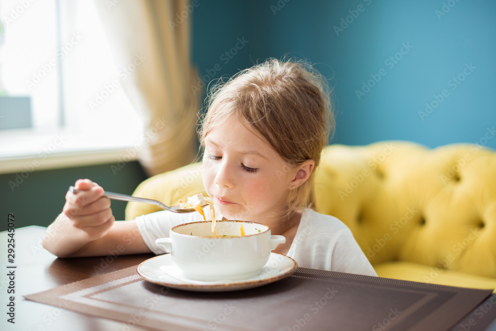 Cute child girl is eating soup in a restaurant Cute child girl is eating soup in a restaurant
