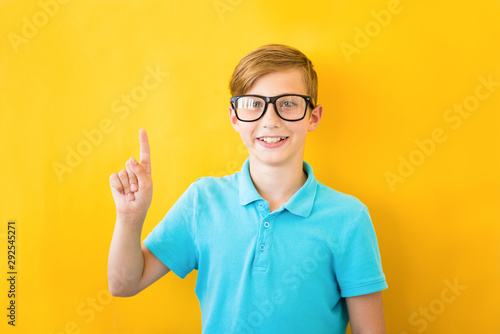 Portrait of stylish little boy with finger pointed up. Kid on yellow blackboard. Success  bright idea  creative ideas and innovation technology concept