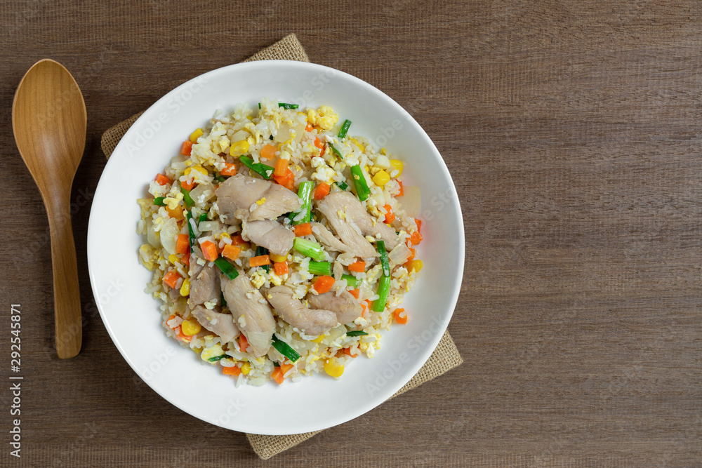 top view of fried rice with chicken and vegetables in a ceramic plate on wooden table. homemade style food concept.