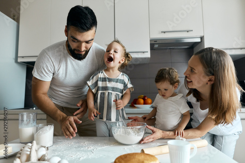 Fotografie cute funny little blonde girl with wide open mouth singing a song while cooking
