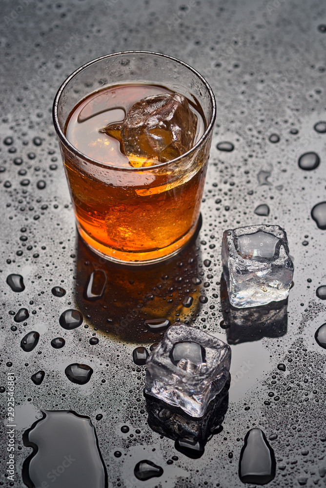 glass of whiskey with ice on a wet surface glass of whiskey with ice on a wet surface