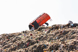 Grabage truck dumping the garbage on large municipal garbage dump in landfill site.