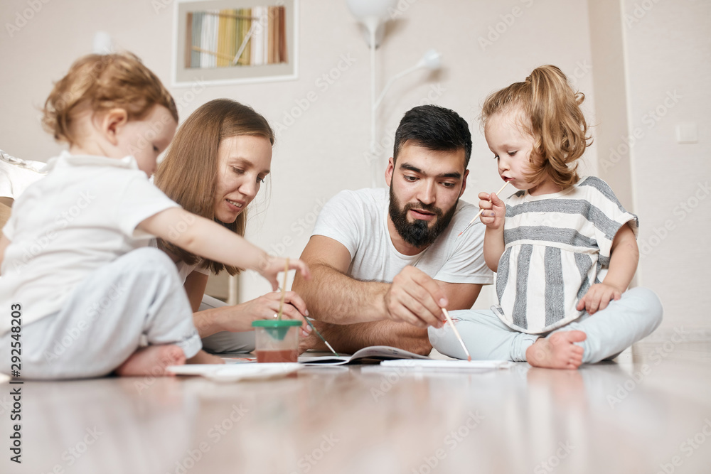 family preparing for art contest, painting a picture while sitting on the floor. closeup photo. family preparing for art contest, painting a picture while sitting on the floor. closeup photo.
