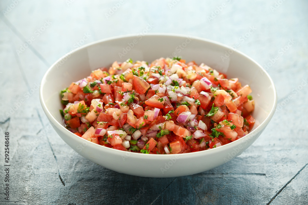 Mexican Tomato Salsa in white bowl with lime, red onion, jalapeno pepper, parsley and tortilla chips Mexican Tomato Salsa in white bowl with lime, red onion, jalapeno pepper, parsley and tortilla chips