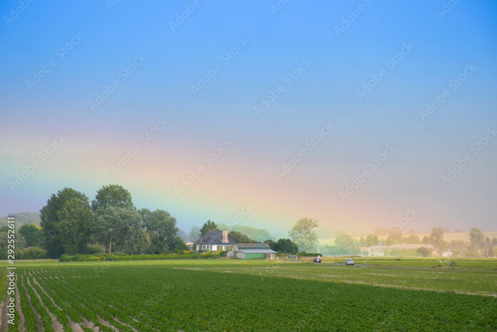 Rainbow after rain at country side on plantation field in France.