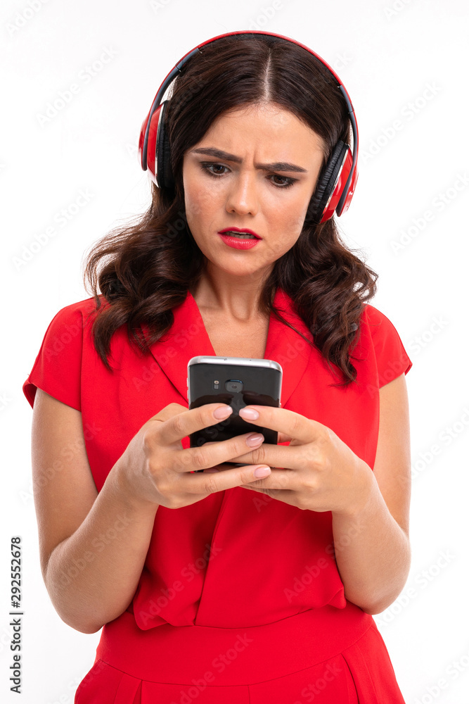 girl in headphones looks at the phone in disbelief girl in headphones looks at the phone in disbelief