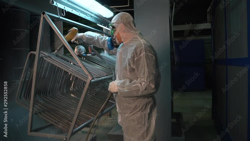 Two men in protective suits treated with a chemical solution metal structure. Two men in protective suits treated with a chemical solution metal structure.