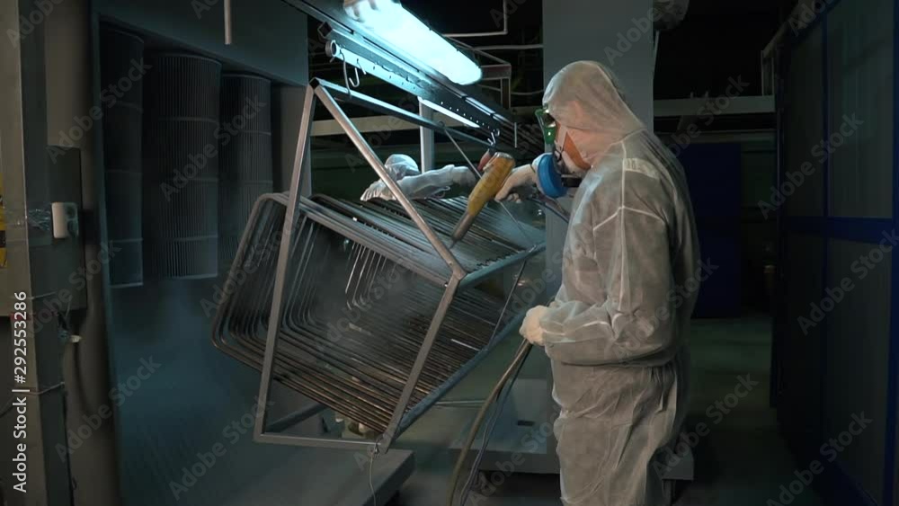 Two men in protective suits treated with a chemical solution metal structure. Two men in protective suits treated with a chemical solution metal structure.