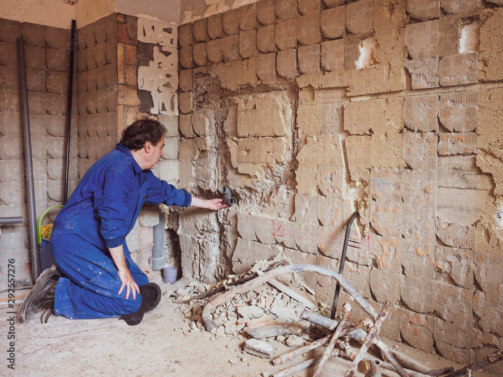 Fototapeta premium Plumber in a kitchen building site, working with PVC pipes.